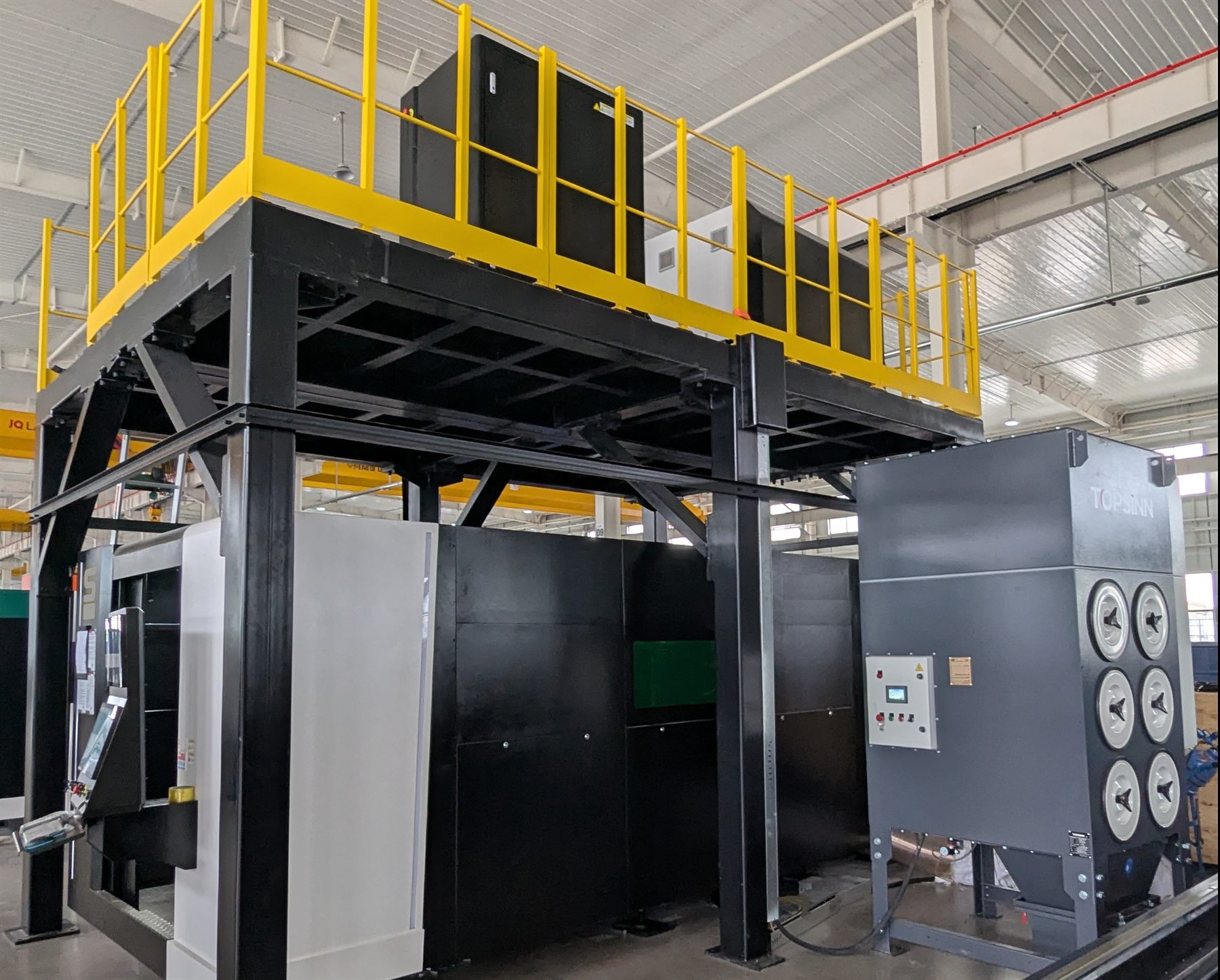 A Topsinn six-cartridge fume dust collector installed alongside an enclosed fibre laser cutting machine and access platform in a fabrication facility.