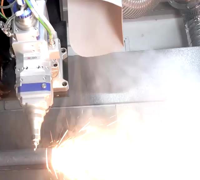 Fume rising from steel section being cut on a tube laser, drawn away by the extraction system
